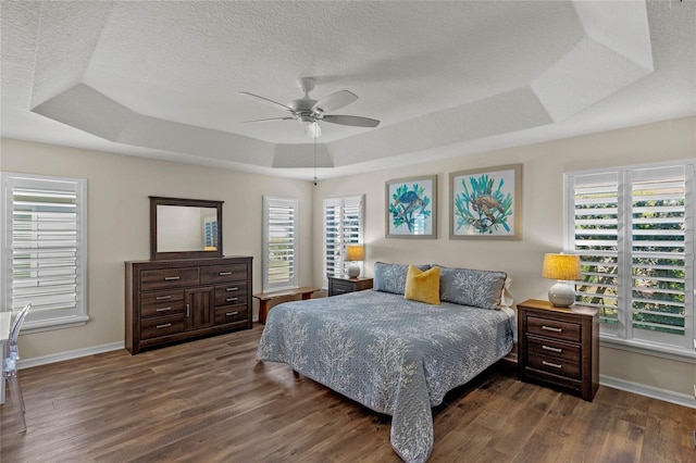 bedroom with ceiling fan, a tray ceiling, and multiple windows