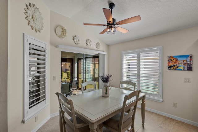 dining room with ceiling fan, lofted ceiling, a textured ceiling, and light tile patterned floors