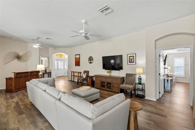 living room featuring dark hardwood / wood-style flooring, a textured ceiling, and ceiling fan