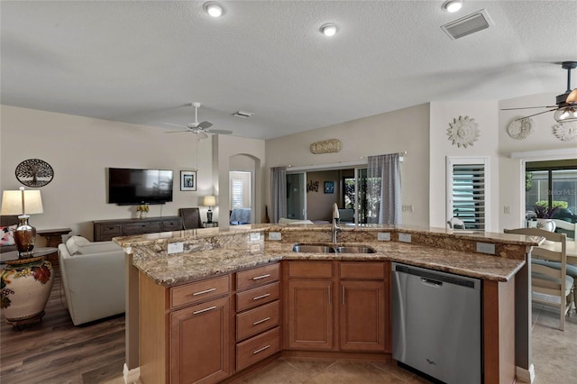 kitchen with sink, dishwasher, ceiling fan, a kitchen island with sink, and a textured ceiling