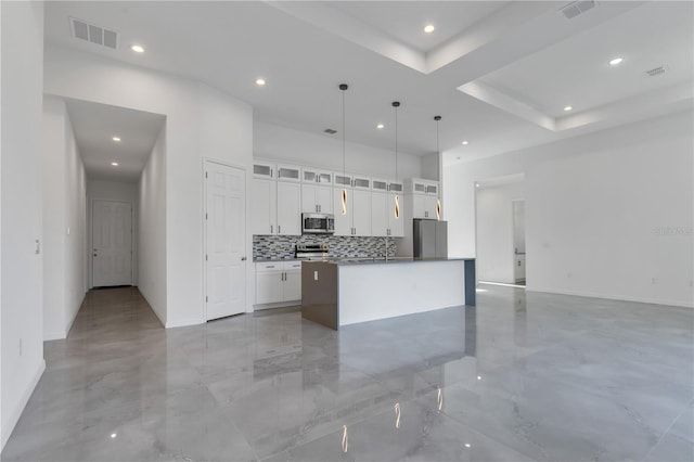 kitchen with white cabinets, tasteful backsplash, decorative light fixtures, a kitchen island, and stainless steel appliances