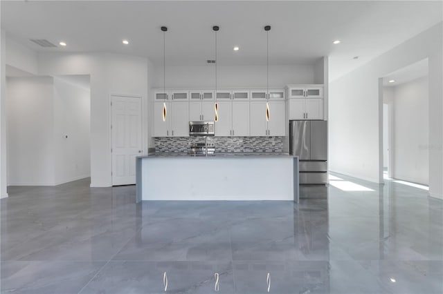 kitchen featuring a kitchen island with sink, hanging light fixtures, white cabinets, and stainless steel appliances