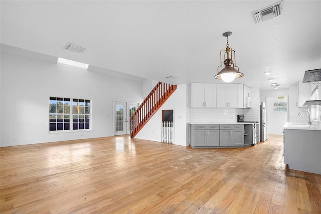 unfurnished living room with light hardwood / wood-style flooring and sink