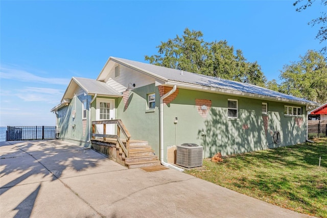 view of front of home with central AC unit and a front lawn