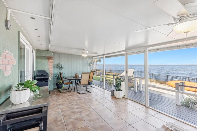 sunroom / solarium with ceiling fan and a water view