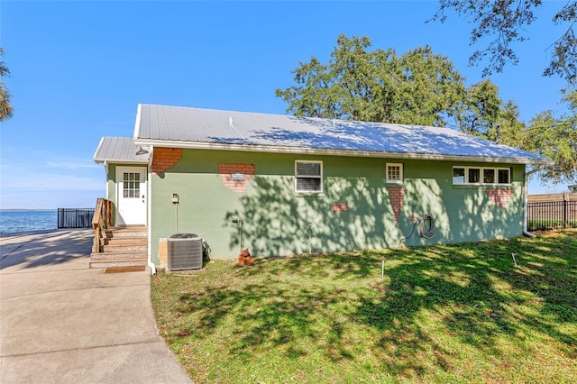 view of front facade featuring a front yard, a water view, and cooling unit