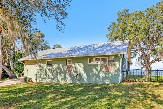 view of side of home with a lawn and central AC unit