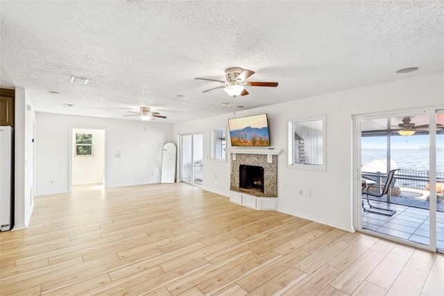 unfurnished living room featuring a high end fireplace, a textured ceiling, light hardwood / wood-style flooring, and ceiling fan