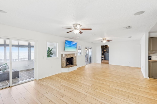 unfurnished living room with a textured ceiling, light wood-type flooring, and a fireplace