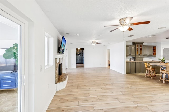 living room featuring a textured ceiling, light wood-type flooring, and ceiling fan