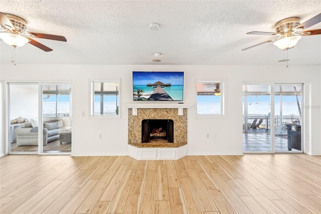 unfurnished living room featuring a healthy amount of sunlight, light hardwood / wood-style floors, and a textured ceiling