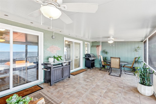 sunroom / solarium with ceiling fan and a water view