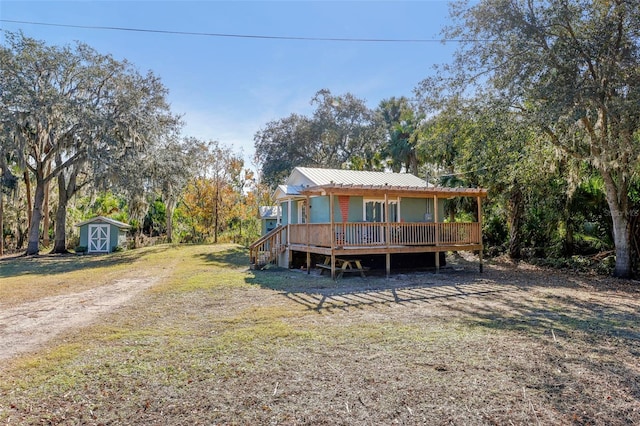 rear view of property featuring a lawn, a wooden deck, and a storage shed