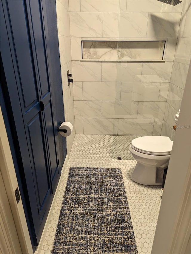 bathroom with tile patterned flooring, a tile shower, and toilet