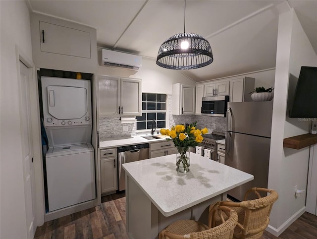 kitchen with dark wood-type flooring, a wall mounted air conditioner, stacked washer / drying machine, decorative backsplash, and appliances with stainless steel finishes