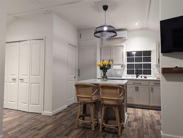 kitchen with pendant lighting, a breakfast bar, dark hardwood / wood-style floors, tasteful backsplash, and a wall unit AC