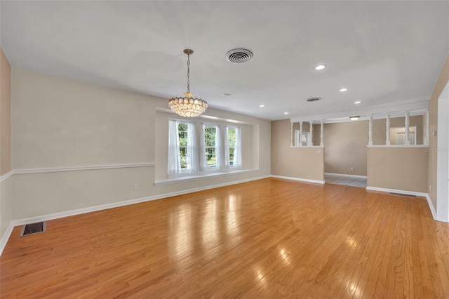 empty room featuring light hardwood / wood-style flooring and a notable chandelier