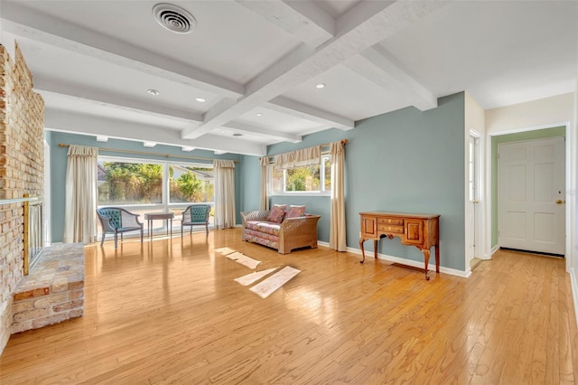 living area with beamed ceiling, coffered ceiling, a fireplace, and light hardwood / wood-style flooring