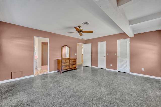 unfurnished bedroom with beamed ceiling, ceiling fan, connected bathroom, and multiple closets