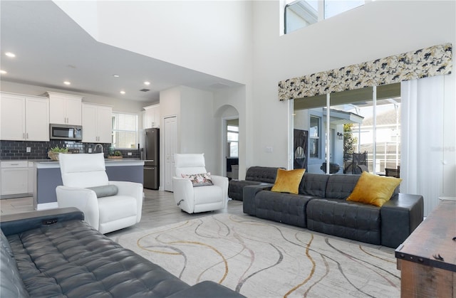 living room featuring light wood-type flooring and a towering ceiling