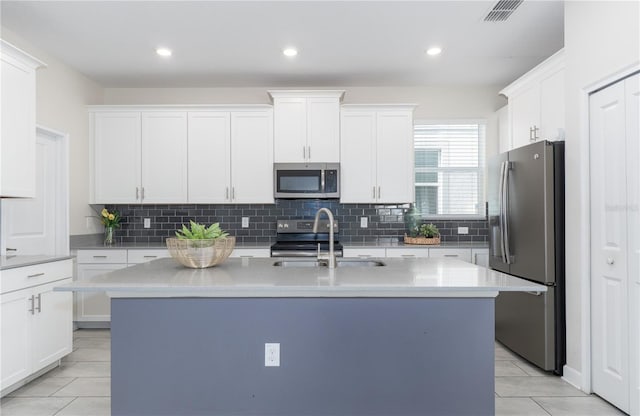 kitchen with appliances with stainless steel finishes, white cabinetry, a kitchen island with sink, and sink