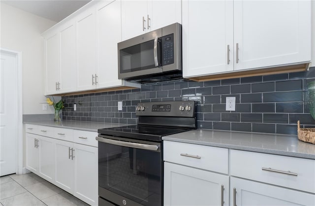 kitchen featuring white cabinetry, light stone counters, decorative backsplash, light tile patterned floors, and appliances with stainless steel finishes