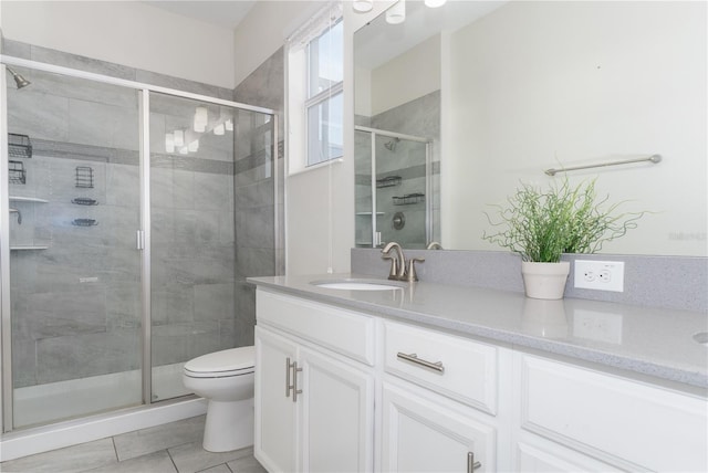 bathroom featuring tile patterned flooring, vanity, toilet, and walk in shower