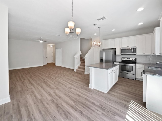 kitchen featuring white cabinets, light wood-style flooring, stainless steel appliances, a sink, and backsplash