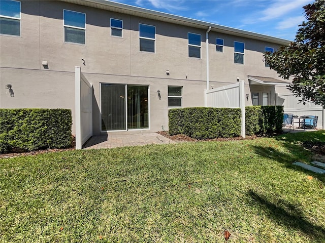rear view of property featuring stucco siding and a lawn