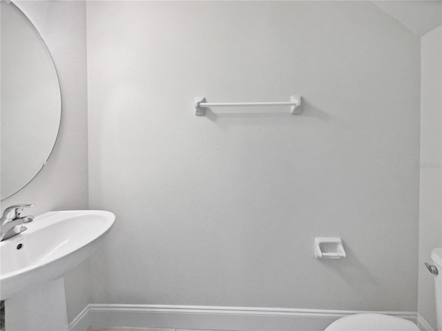 half bath with a sink, baseboards, and toilet