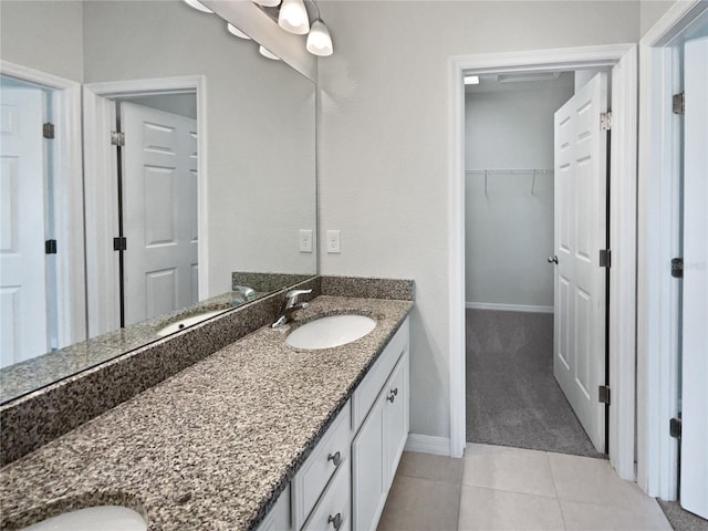 bathroom with tile patterned floors, a walk in closet, baseboards, and vanity