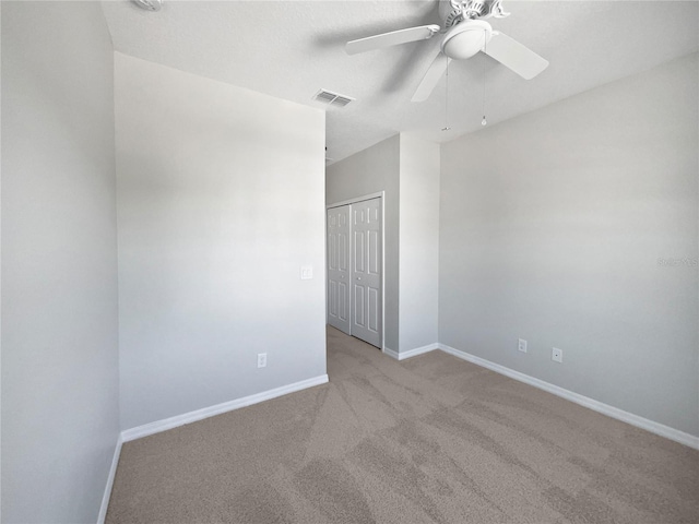 unfurnished room featuring carpet floors, baseboards, visible vents, and ceiling fan