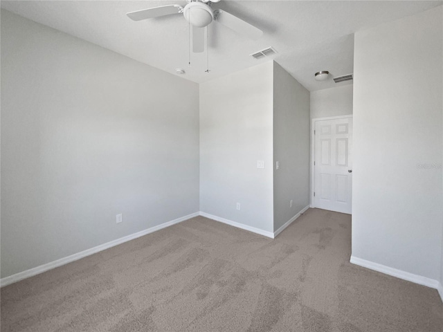 empty room with carpet flooring, baseboards, ceiling fan, and visible vents
