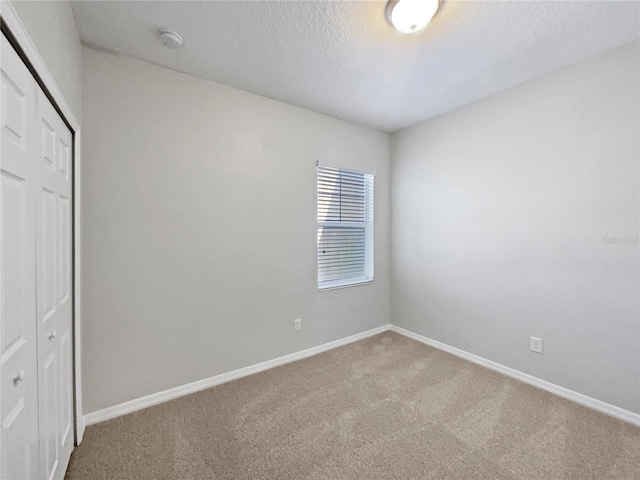 unfurnished bedroom with baseboards, a closet, carpet flooring, and a textured ceiling