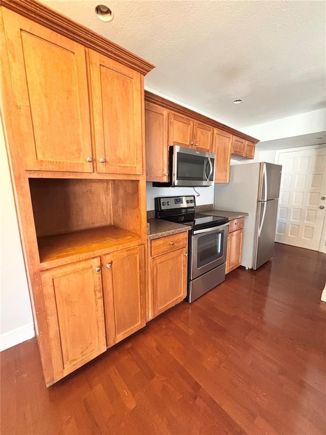 kitchen featuring dark wood-type flooring, a textured ceiling, and appliances with stainless steel finishes