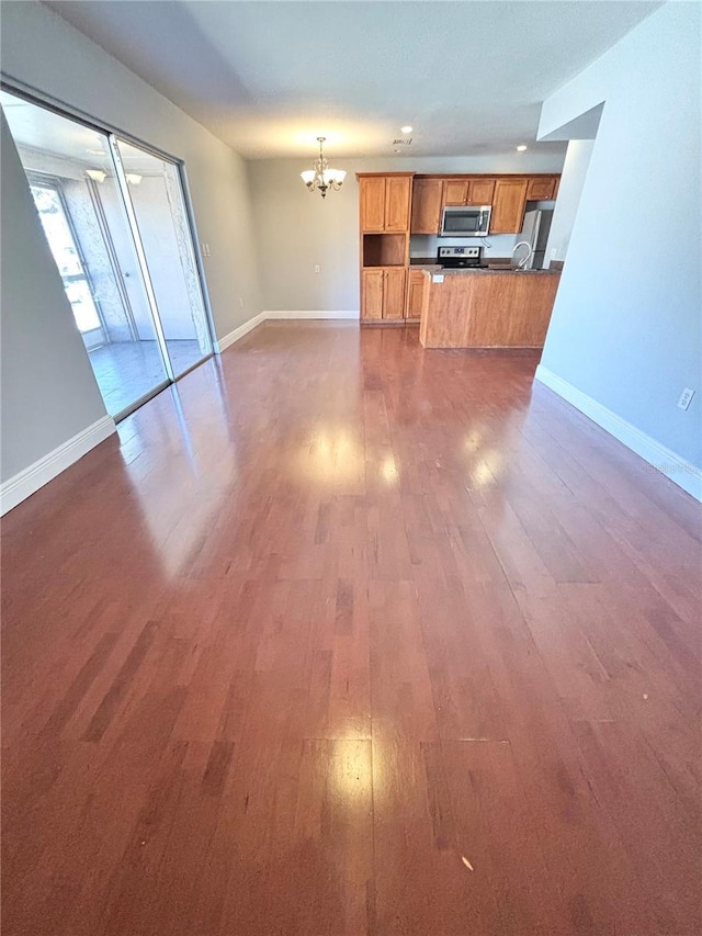 unfurnished living room featuring dark hardwood / wood-style flooring and a chandelier