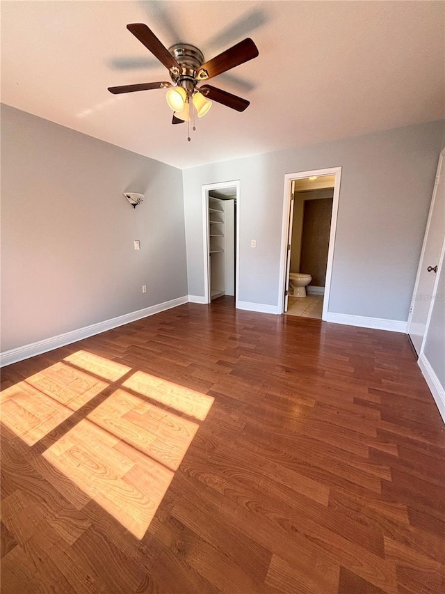 unfurnished bedroom with ensuite bathroom, ceiling fan, a spacious closet, dark hardwood / wood-style floors, and a closet