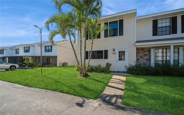 townhome / multi-family property featuring central AC unit and a front lawn