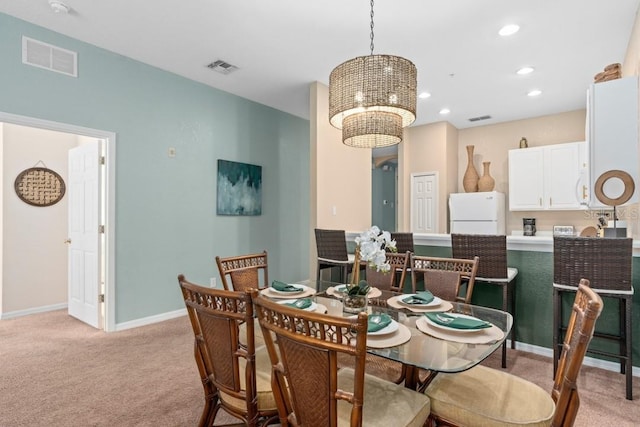 dining area with light carpet and a chandelier