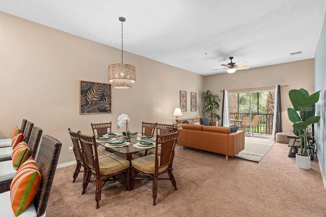 carpeted dining room featuring ceiling fan with notable chandelier