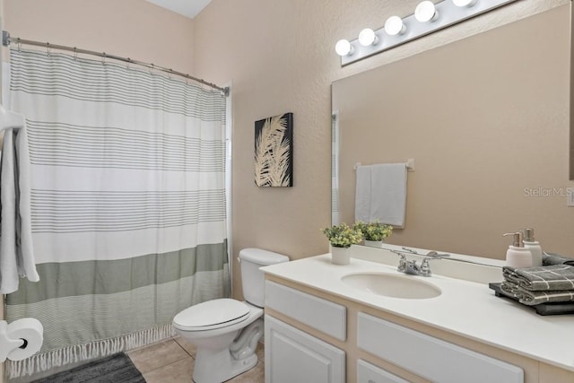 bathroom with toilet, vanity, and tile patterned floors