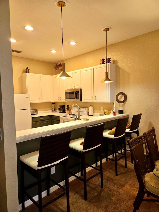 kitchen with hanging light fixtures, white appliances, a kitchen bar, white cabinets, and dark carpet