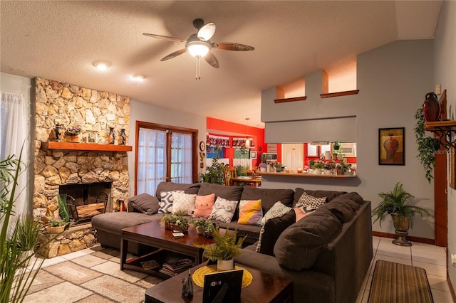 tiled living room with a textured ceiling, high vaulted ceiling, a stone fireplace, and ceiling fan