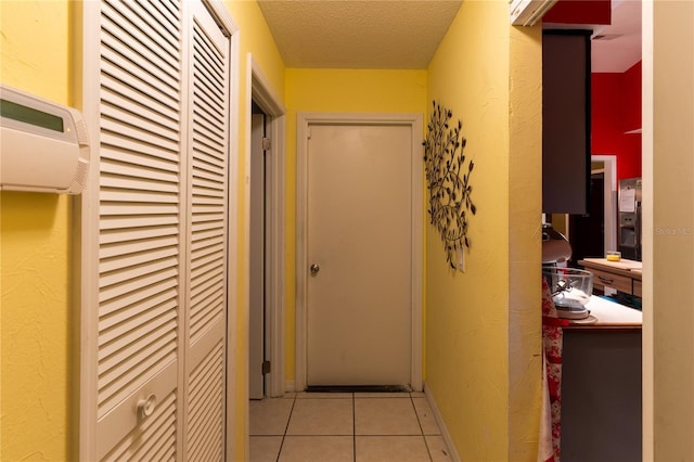 corridor with light tile patterned floors, a textured ceiling, and a wall mounted AC