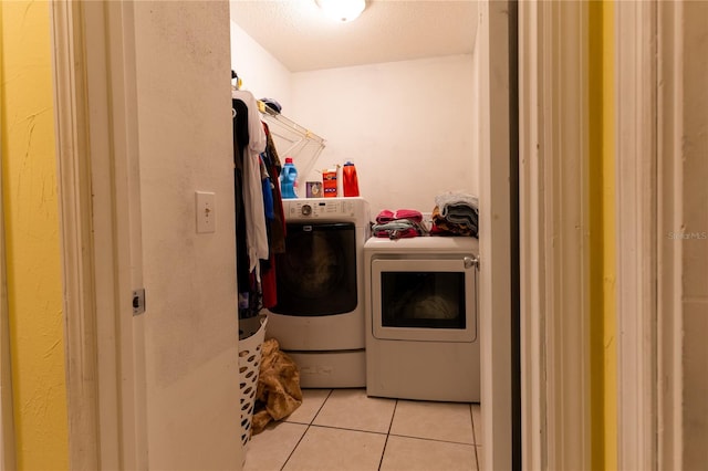 laundry area featuring light tile patterned floors, washing machine and dryer, and a textured ceiling