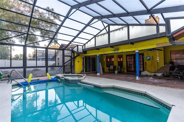 view of swimming pool with glass enclosure, an in ground hot tub, and a patio