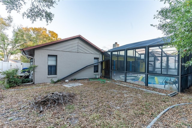 rear view of house featuring a lanai and a fenced in pool