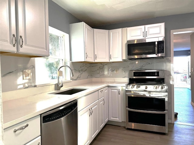 kitchen with sink, white cabinetry, stainless steel appliances, and light hardwood / wood-style flooring