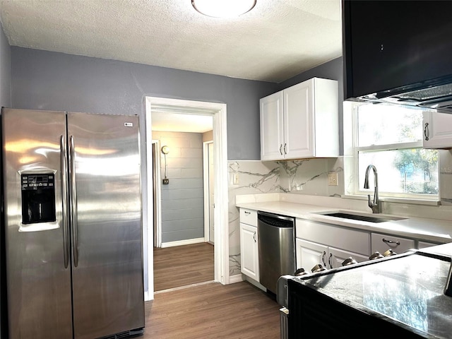 kitchen with white cabinets, sink, a textured ceiling, wood-type flooring, and stainless steel appliances