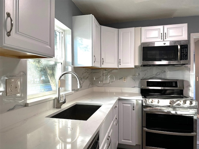 kitchen with stainless steel appliances, white cabinetry, tasteful backsplash, and sink